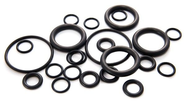 Black rubber O-rings of varying sizes scattered on a white surface.