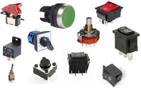 Collection of various electronic switches and buttons, in different colors and designs. Switches on-off, illuminated buttons/push-buttons, coils.