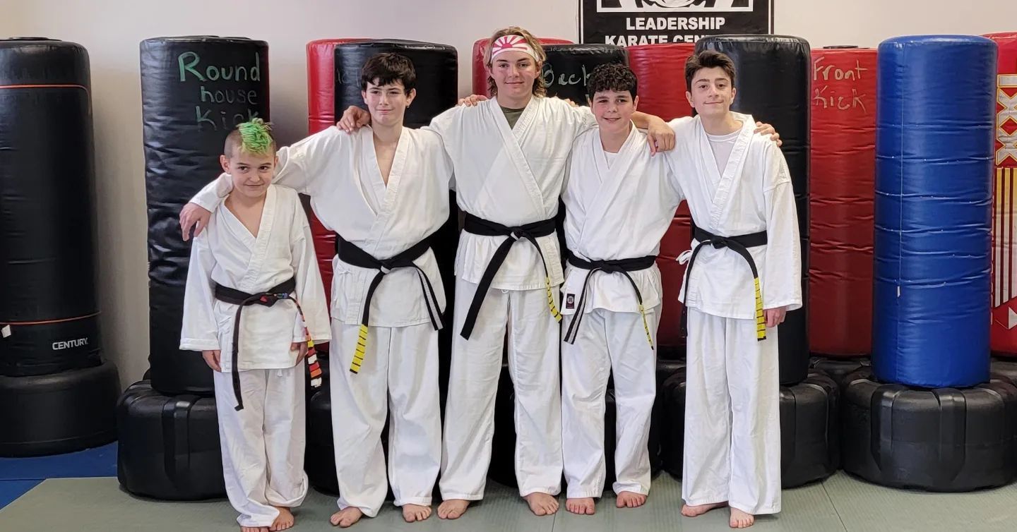 A group of young men in karate uniforms are posing for a picture.