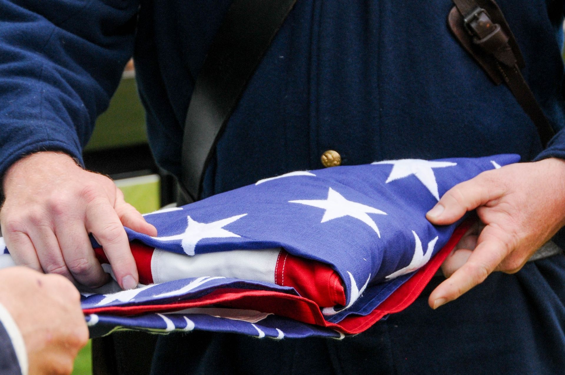 A woman is holding an american flag and a rose at a funeral.