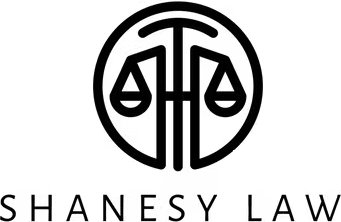 Black circular law firm logo with scales of justice and the text “SHANESY LAW” below.