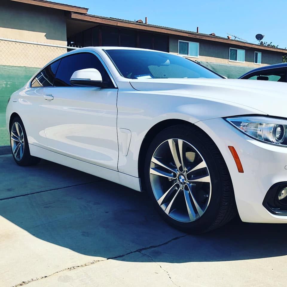 White coupe parked in a sunny driveway beside a house