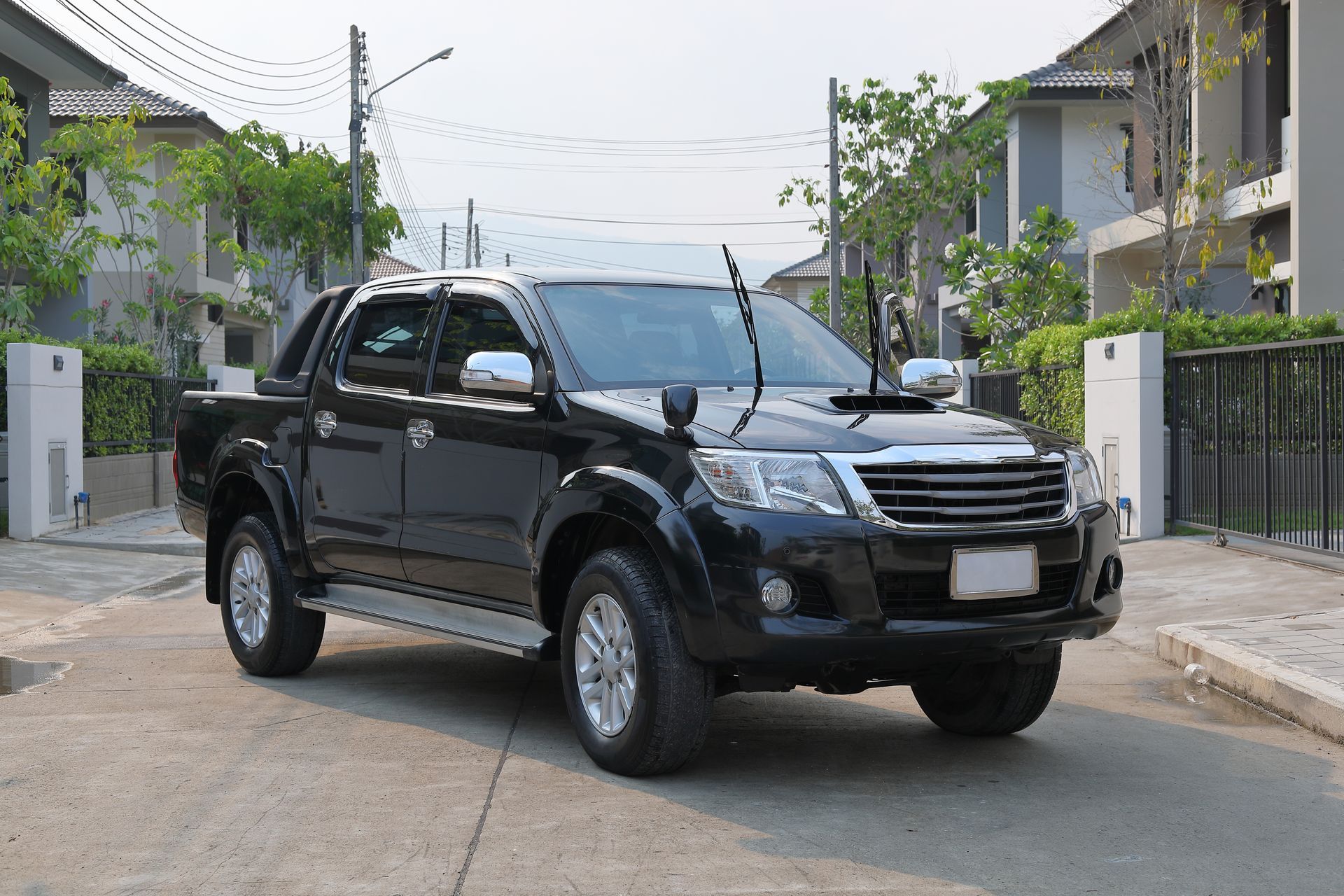 Black pickup truck driving on a residential street with houses and power lines