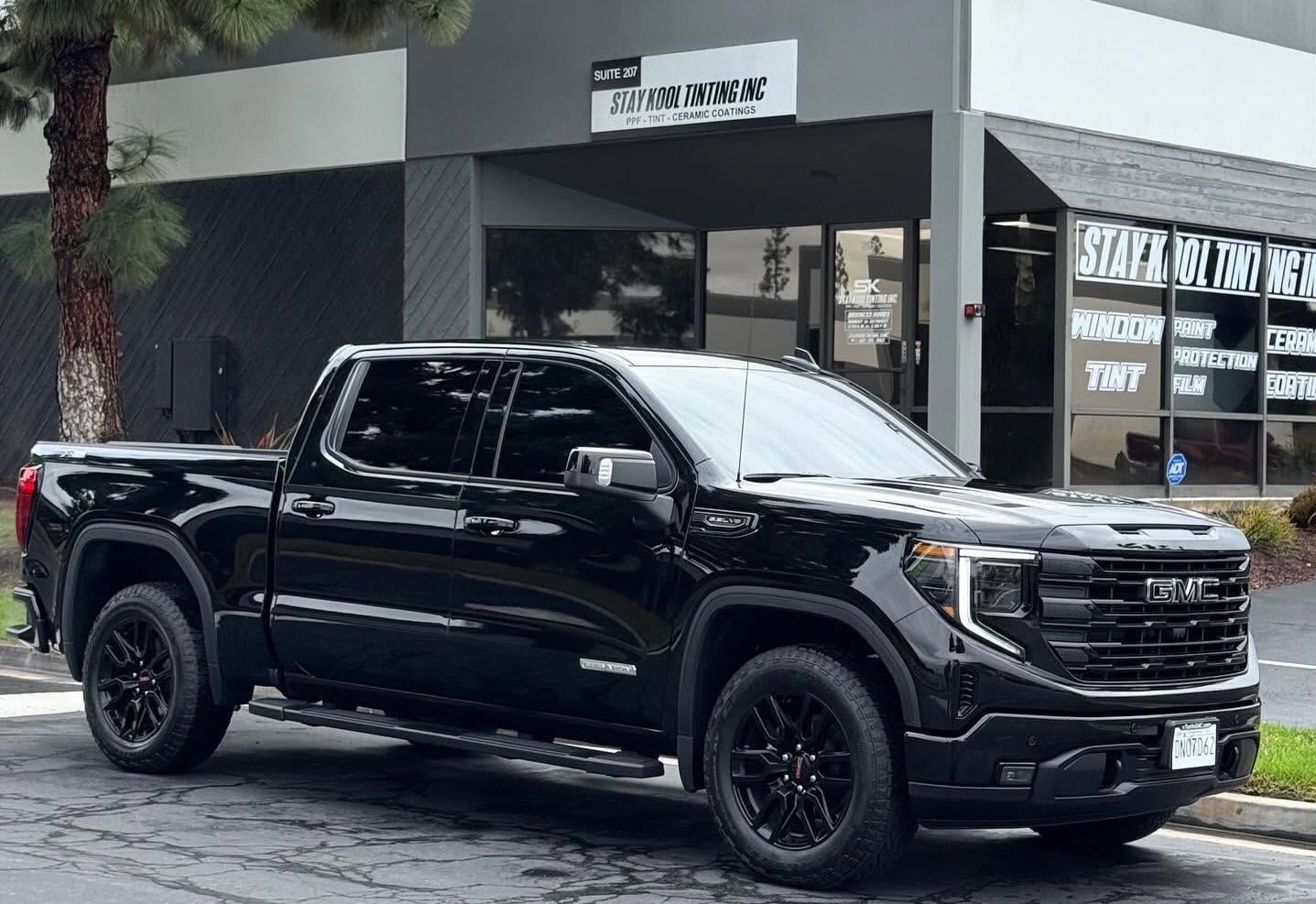 Black electric SUV parked in front of a white building with garage-style doors.
