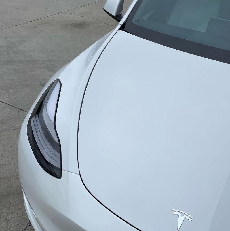 Front-left view of a white Tesla car parked on a concrete surface