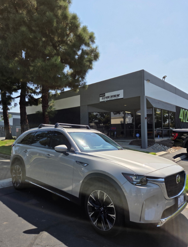 White SUV parked outside a car dealership under a clear sky.