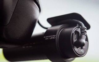 Close-up of a black action camera mounted on a vehicle or equipment, with visible lens and branding.