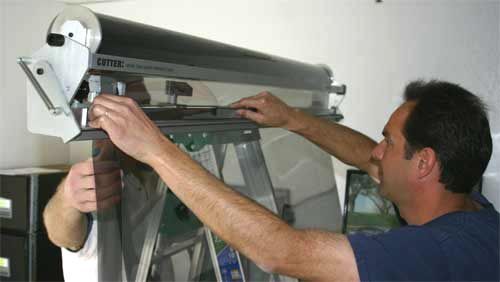 Man adjusting a clear plastic cover on a large metal machine
