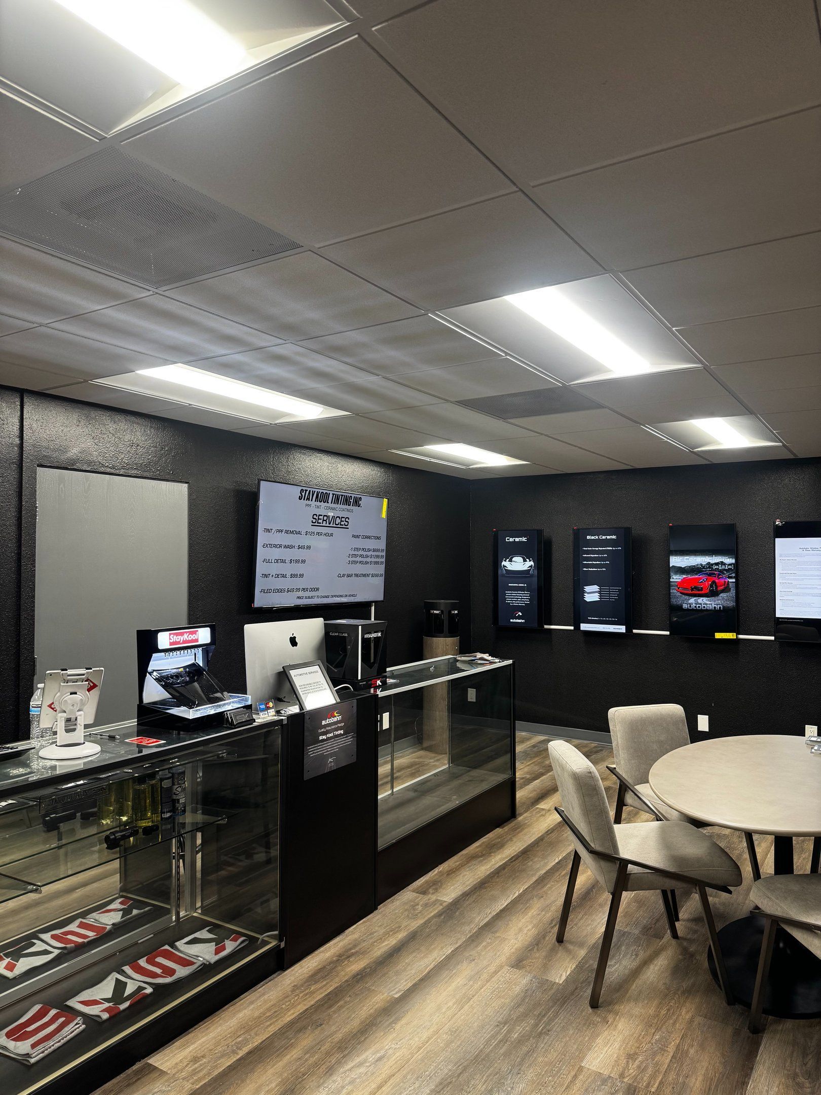 Modern lounge with counter, beverage coolers, round table, and chairs under bright ceiling lights.