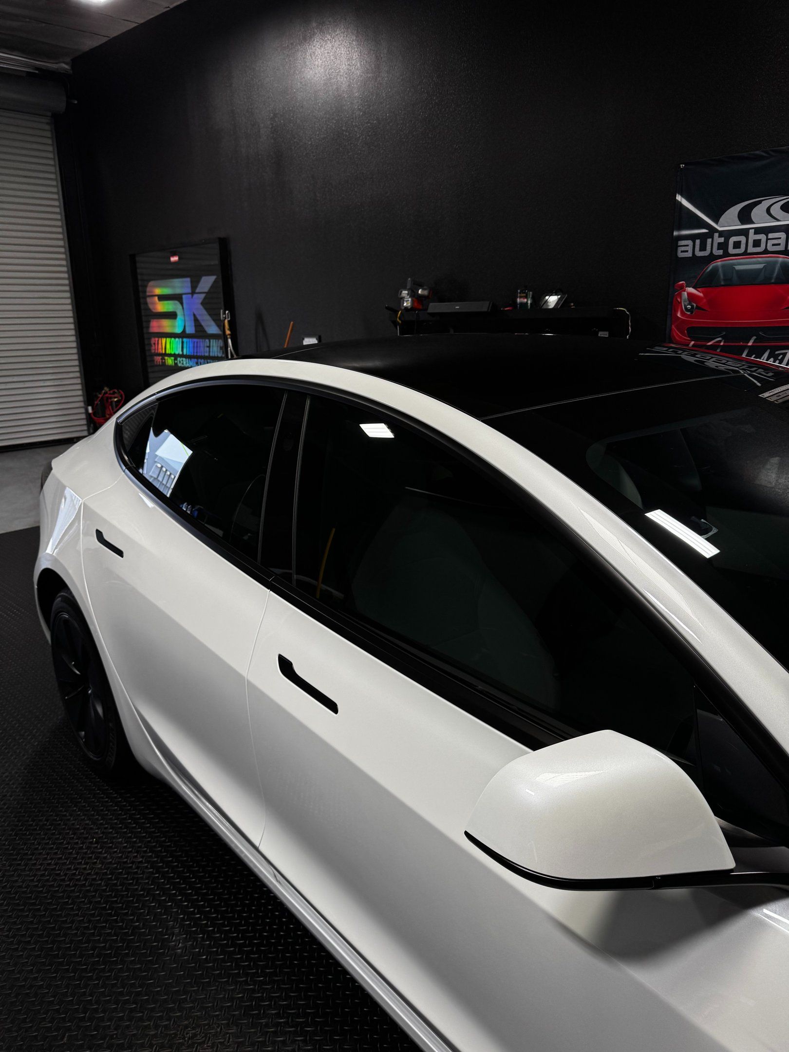 White sedan in a dark garage with tinted windows and a black roof accent
