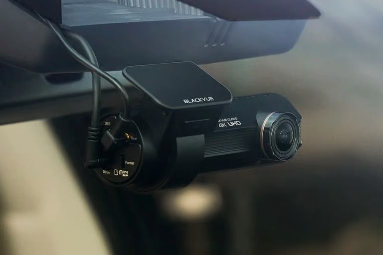 Dashboard camera mounted on a car windshield with cables attached
