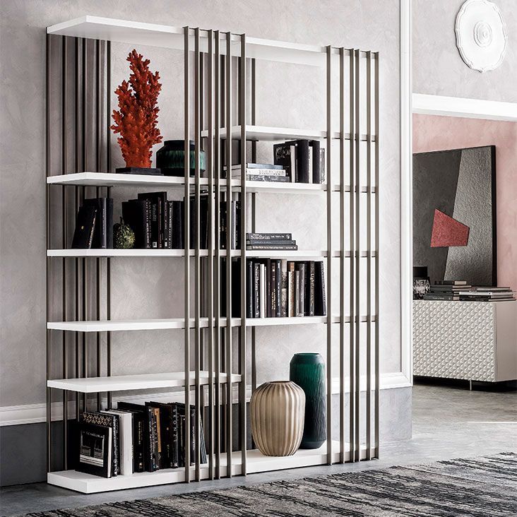 Sala de estar moderna con una estantería blanca, jarrones decorativos, libros y detalles metálicos verticales altos.