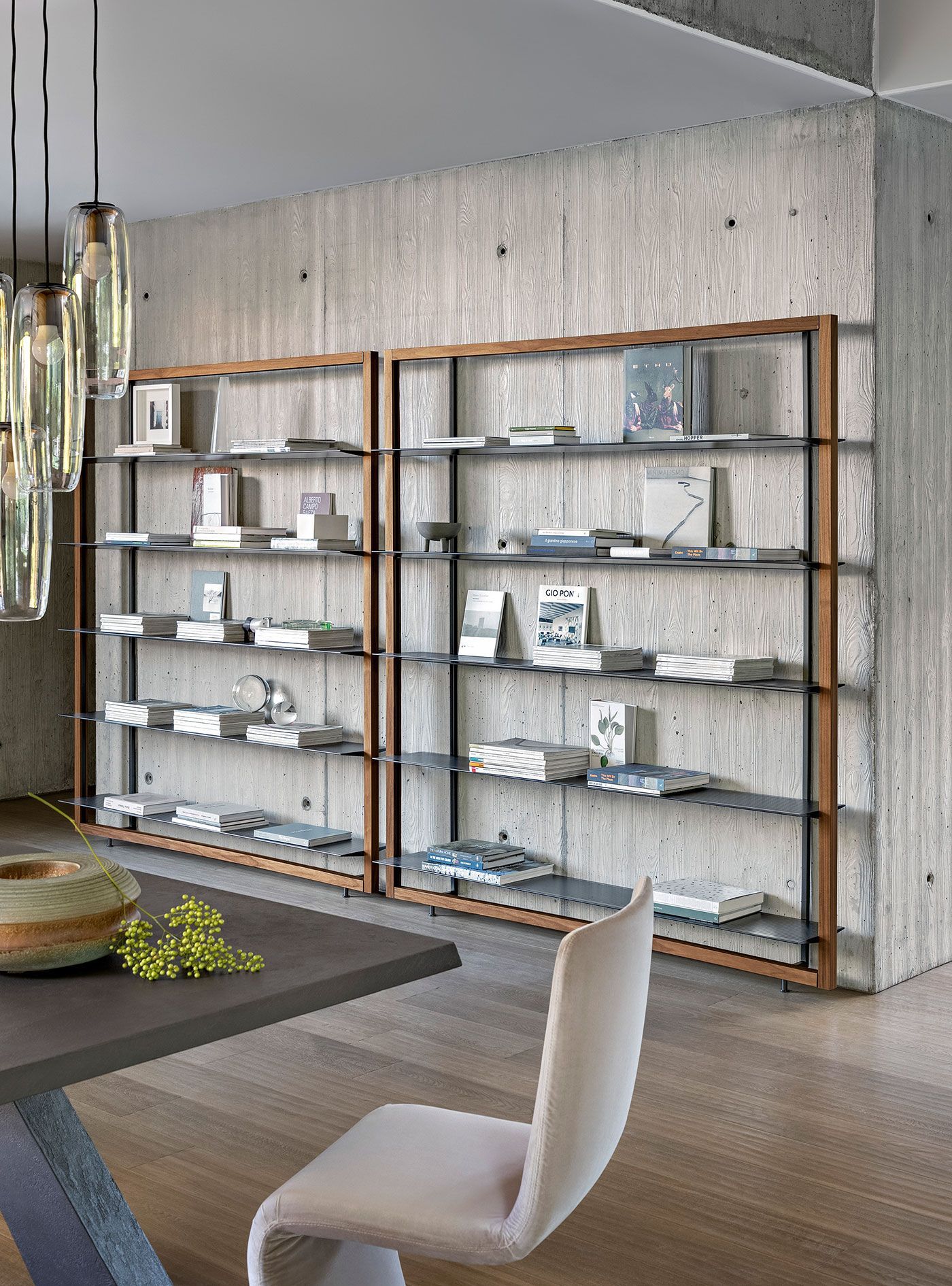 Sala de estar moderna con estantes de madera que exhiben libros y elementos decorativos contra una pared de hormigón.
