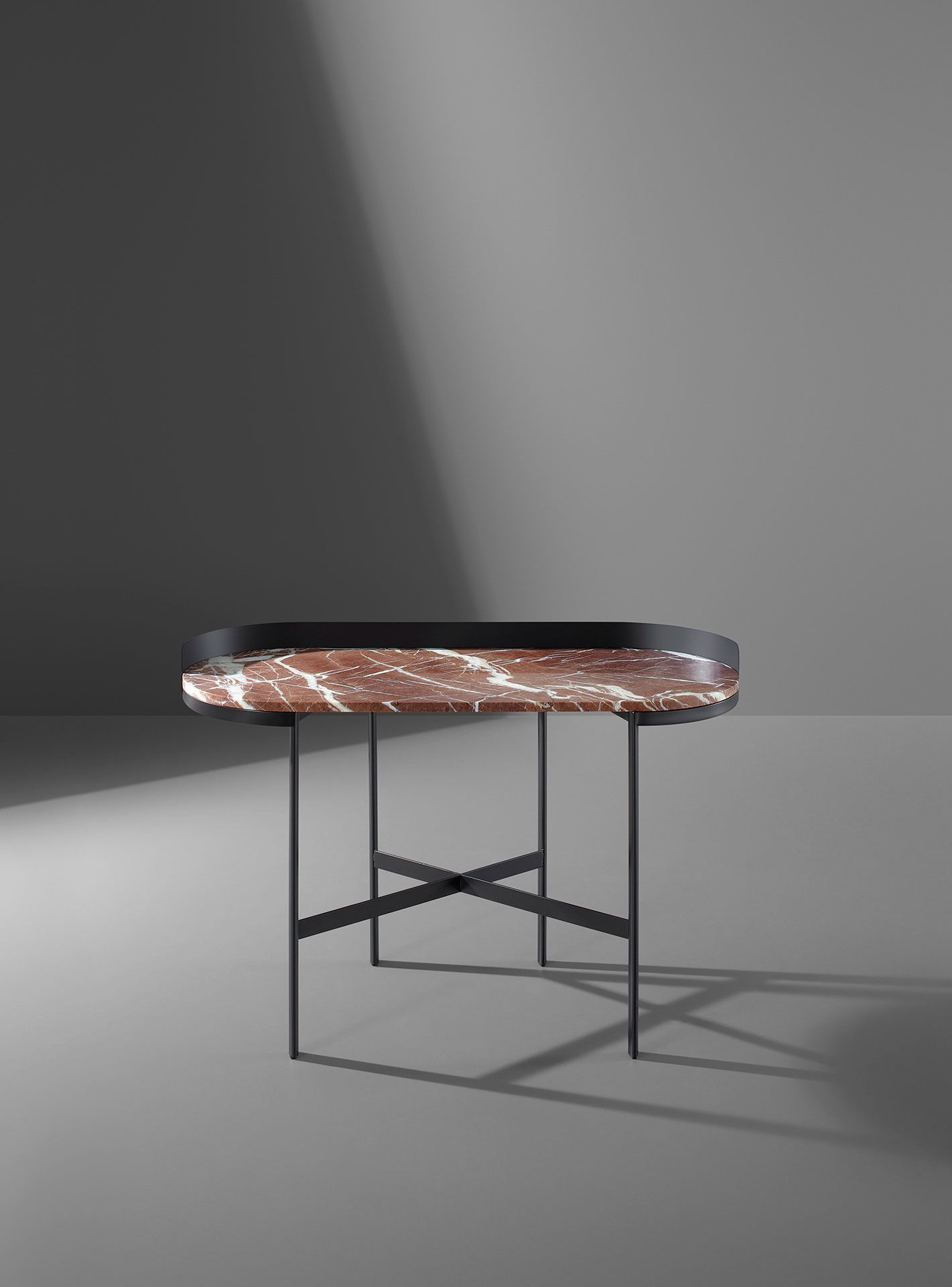 Mesa auxiliar redonda moderna con estructura de metal oscuro y tablero de mármol sobre fondo gris.