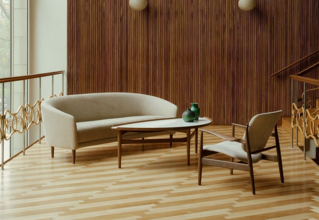 Salón moderno con sofá beige, mesa de centro de madera, sillón y pared revestida de listones de madera