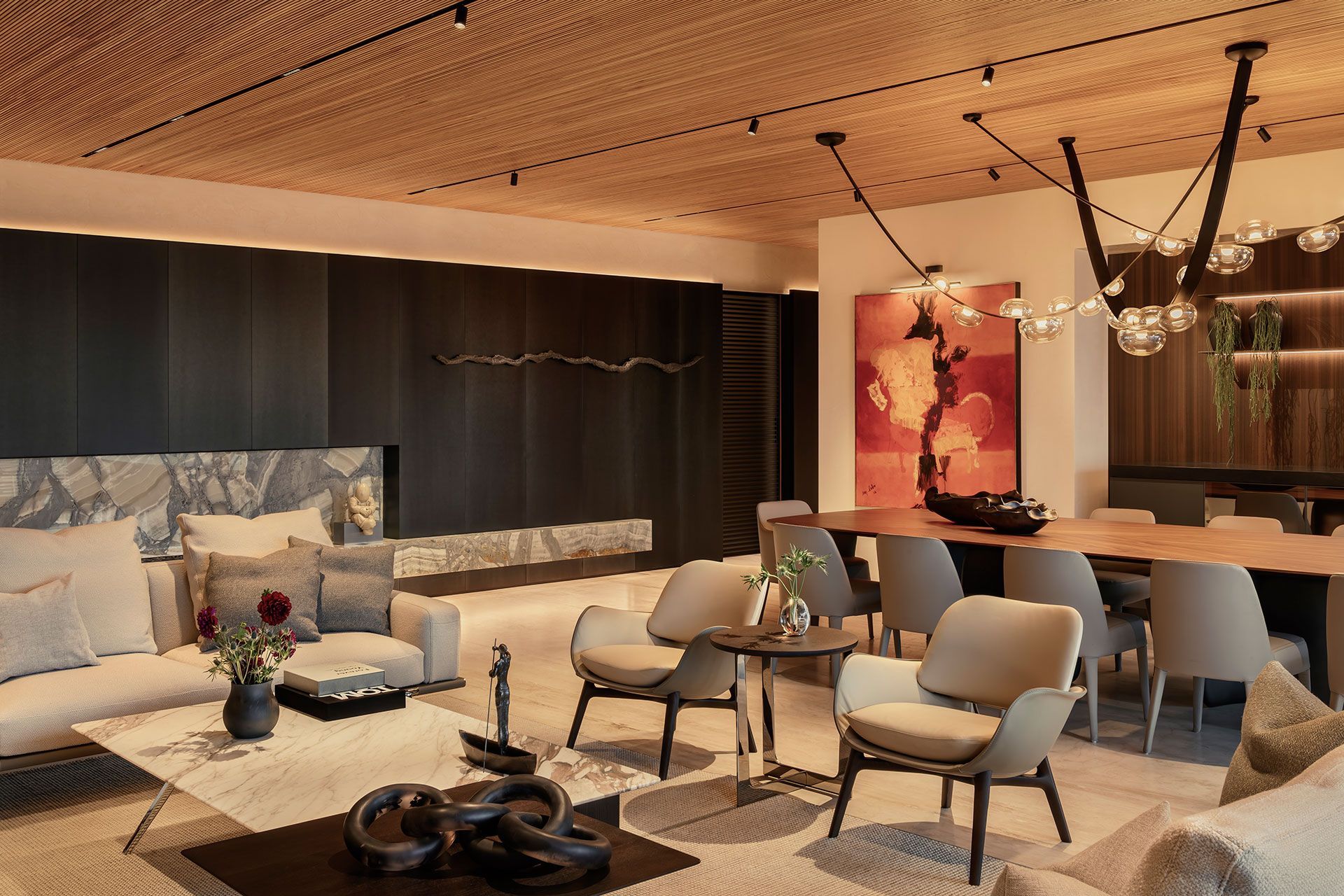 Salón-comedor moderno con sofá gris, mesa larga de madera y luces de la ciudad por la noche.