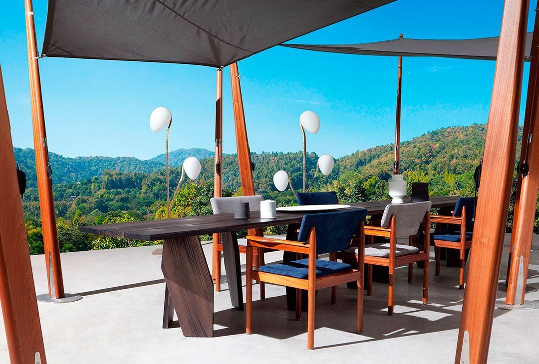 Patio exterior con mesa de madera, sillas y sombrilla, ideal para comer al aire libre