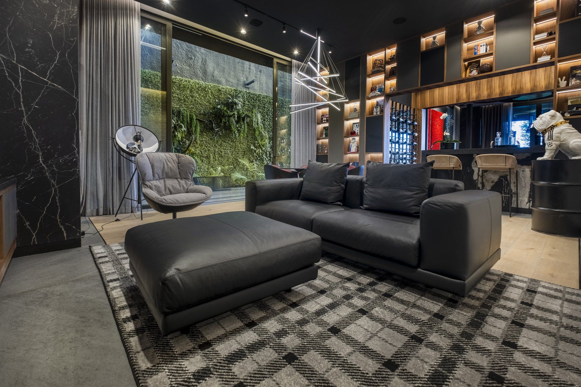 Salón de lujo moderno con sofá seccional negro, chaise longue, alfombra estampada y pared de cristal del suelo al techo.