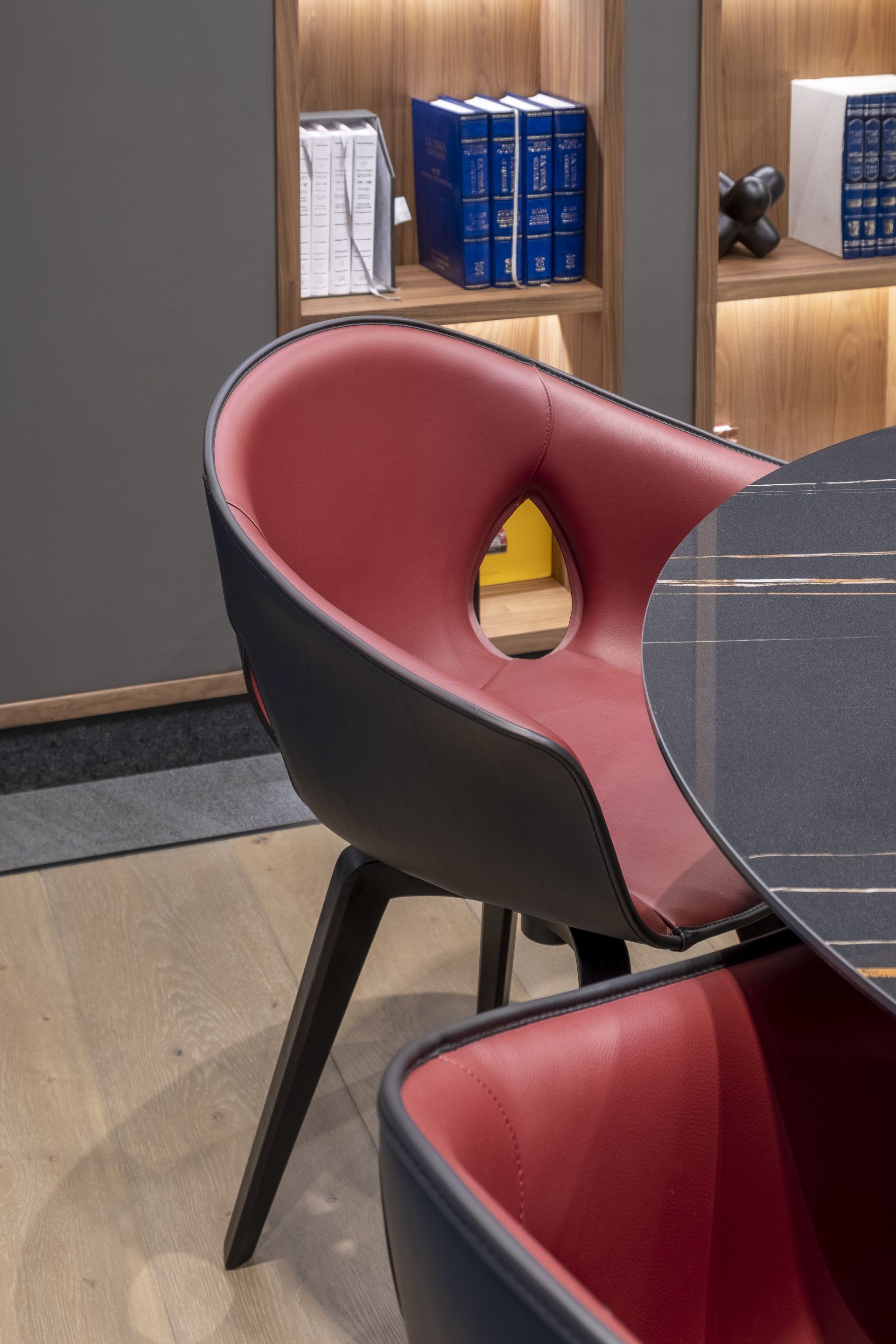 Silla roja y negra junto a una mesa redonda en una habitación moderna con paneles de madera.