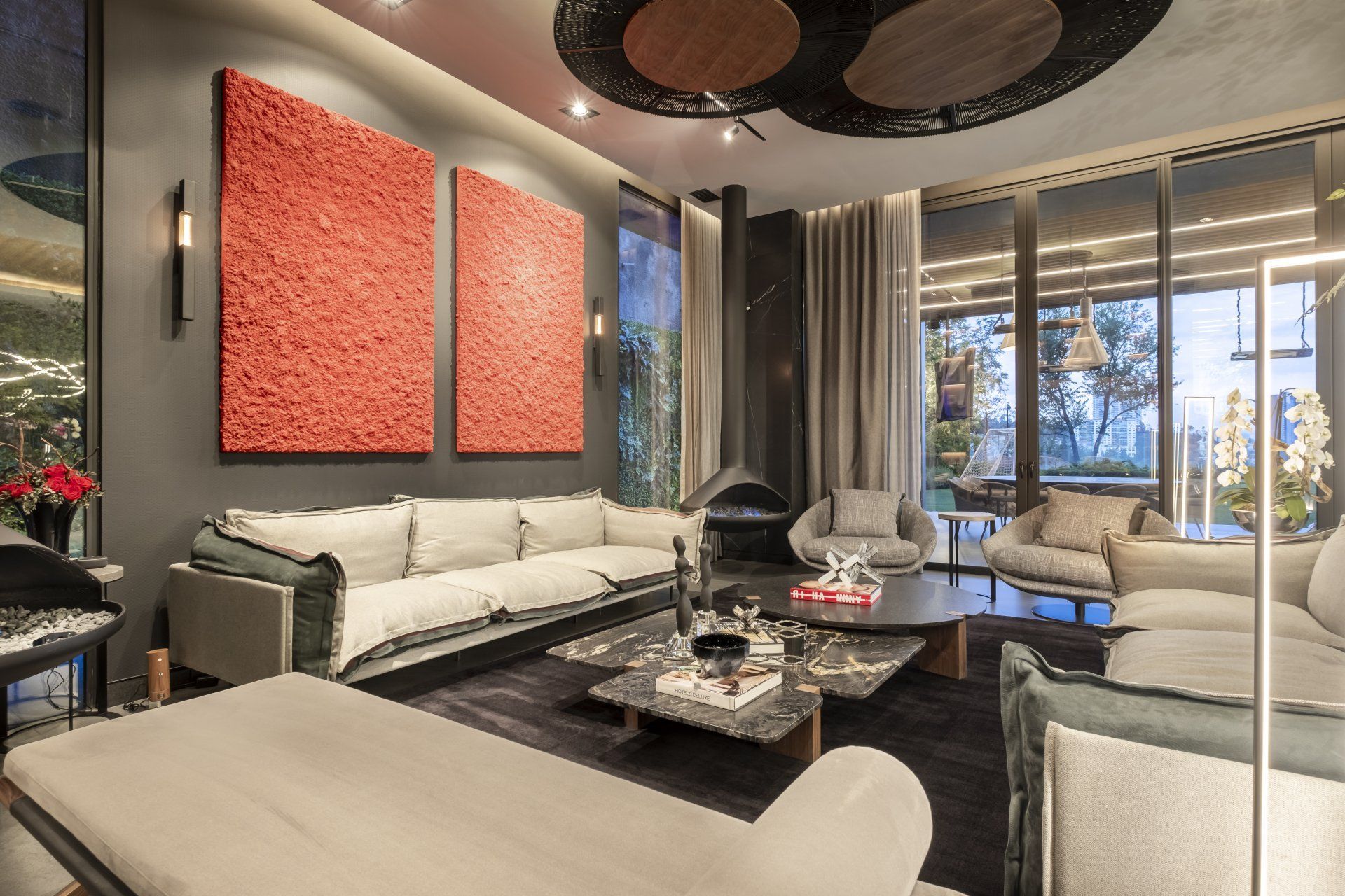 Sala de estar moderna con sofás blancos, mesa de centro negra y cuadro de coral cerca de grandes ventanales.