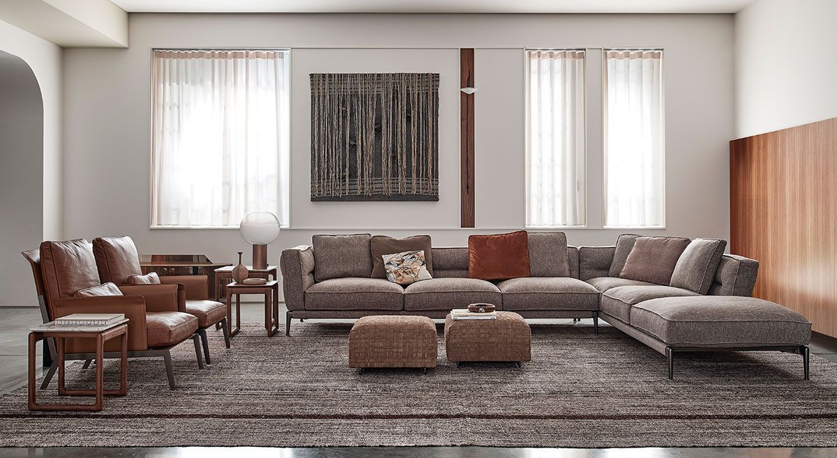Sala de estar moderna con un gran sofá modular gris, sillas marrones, otomanas tejidas