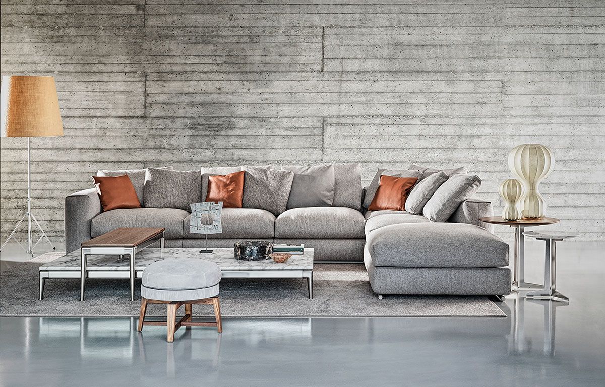 Sofá modular moderno de color gris con cojines naranjas en una sala de estar minimalista