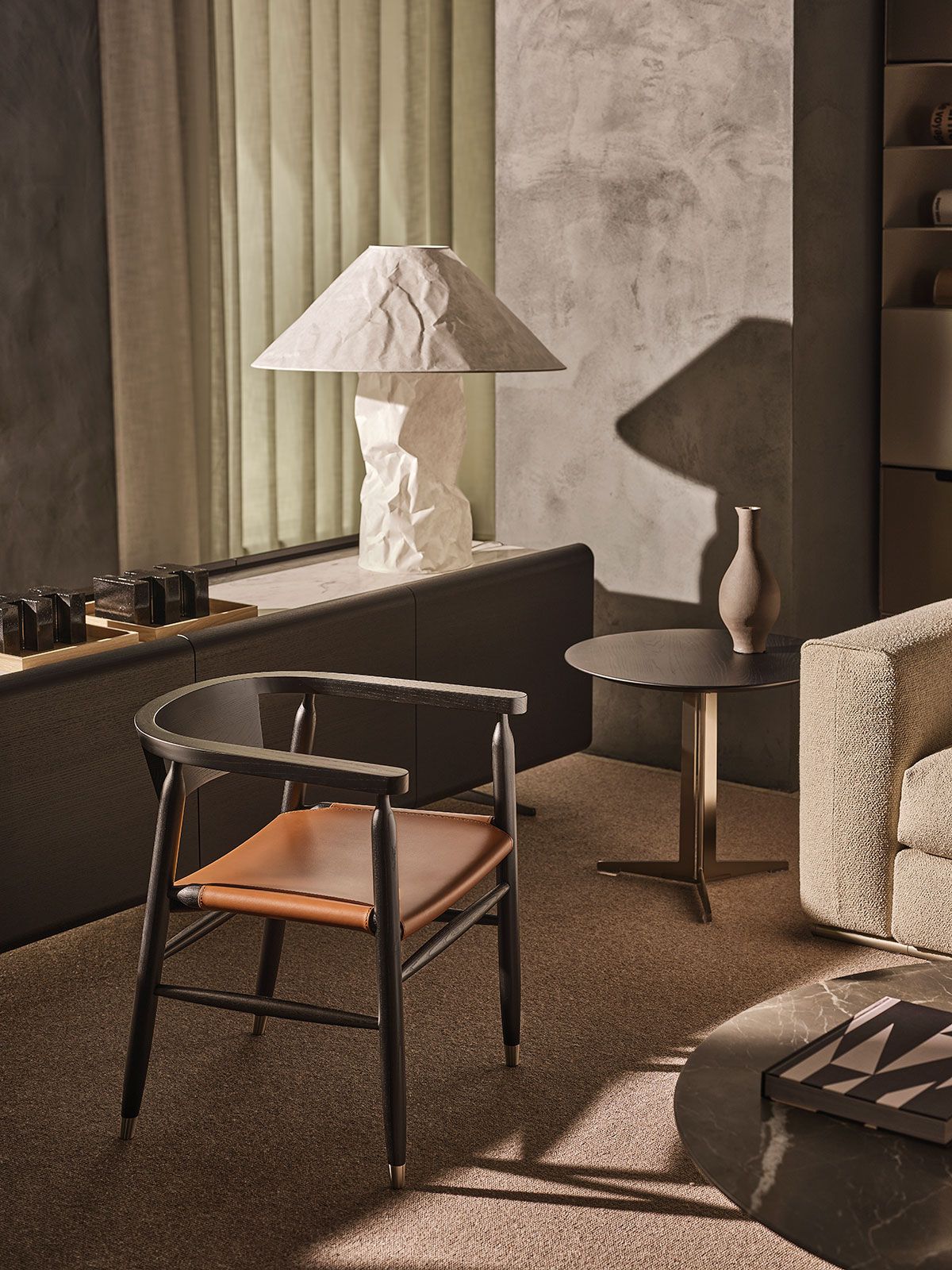 Acogedora sala de estar con una lámpara sobre un mueble, una silla y luz solar cálida que proyecta sombras sobre paredes