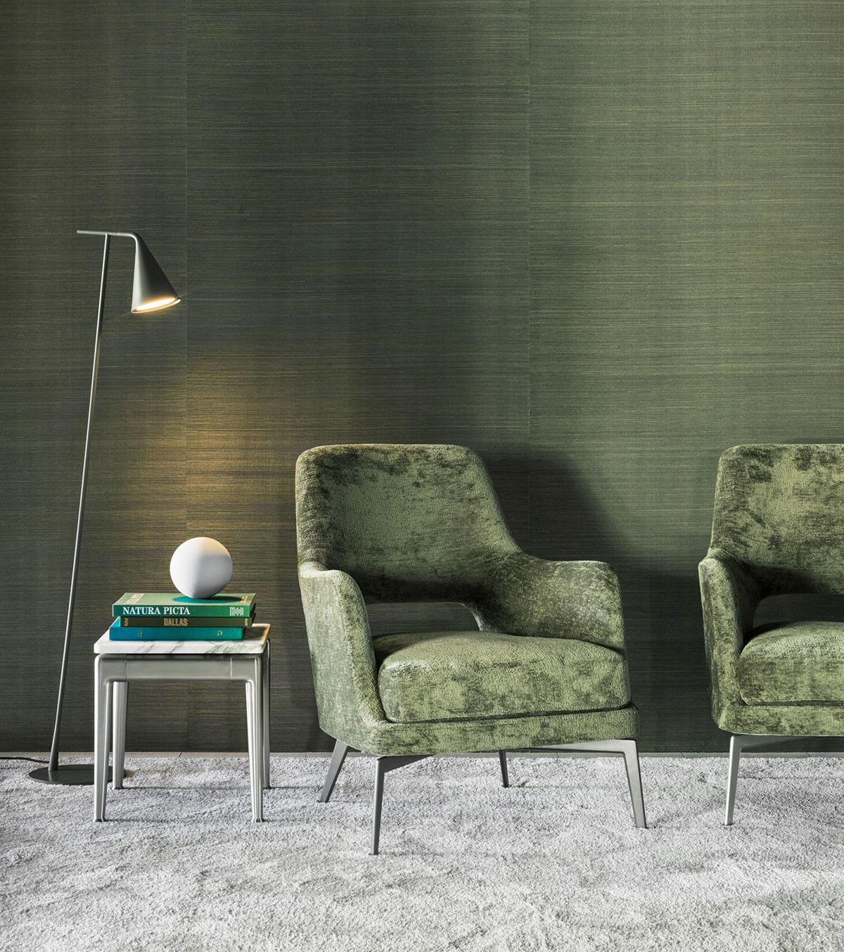 Sala de estar moderna con sillones de terciopelo verde, una mesa auxiliar y una lámpara de pie sobre una alfombra gris.