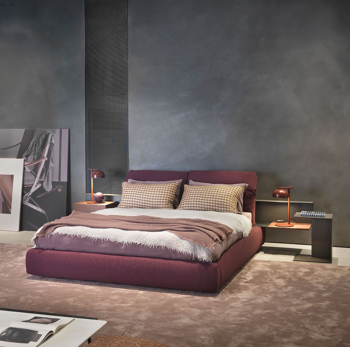 Dormitorio moderno con cama color burdeos, almohadas estampadas y paredes gris oscuro.