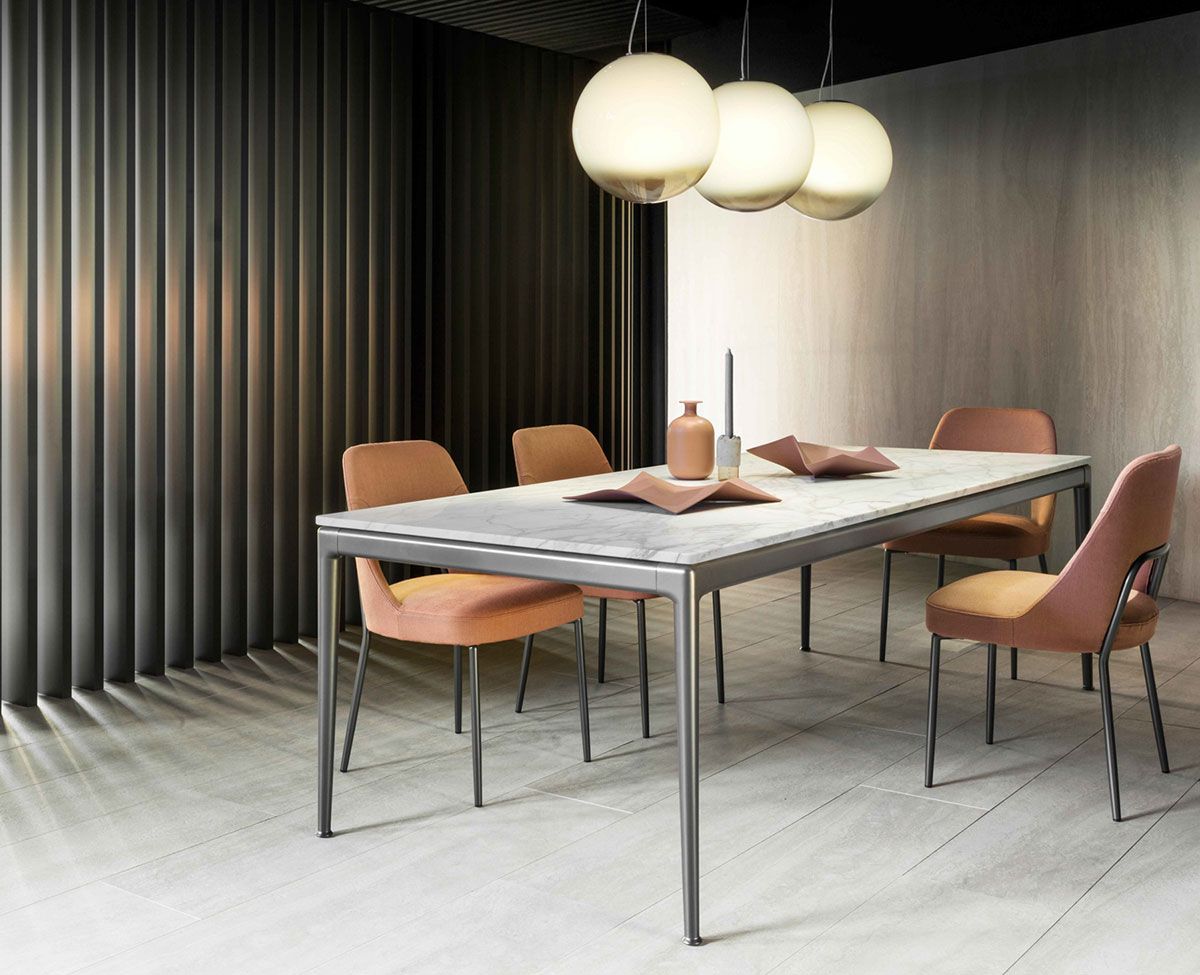 Comedor moderno con mesa, cuatro sillas, lámparas colgantes y cortinas oscuras.