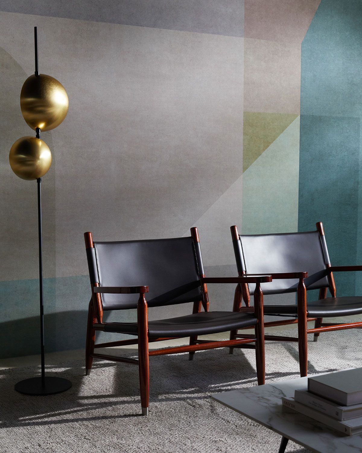 Dos sillones negros y una lámpara de pie de latón en una habitación moderna y minimalista.