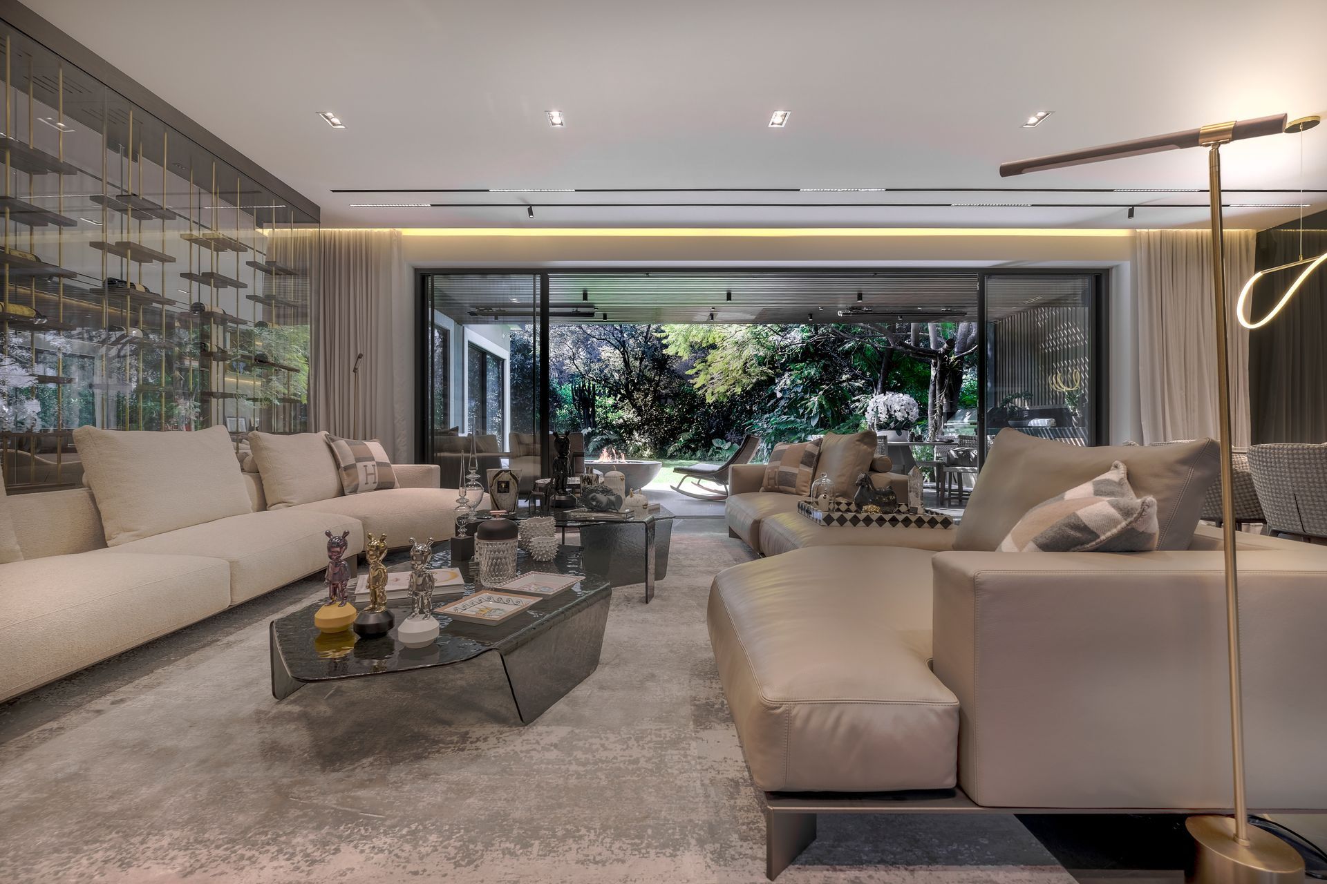 Sala de estar moderna y lujosa con sofás seccionales beige, mesa de centro de cristal y grandes ventanales
