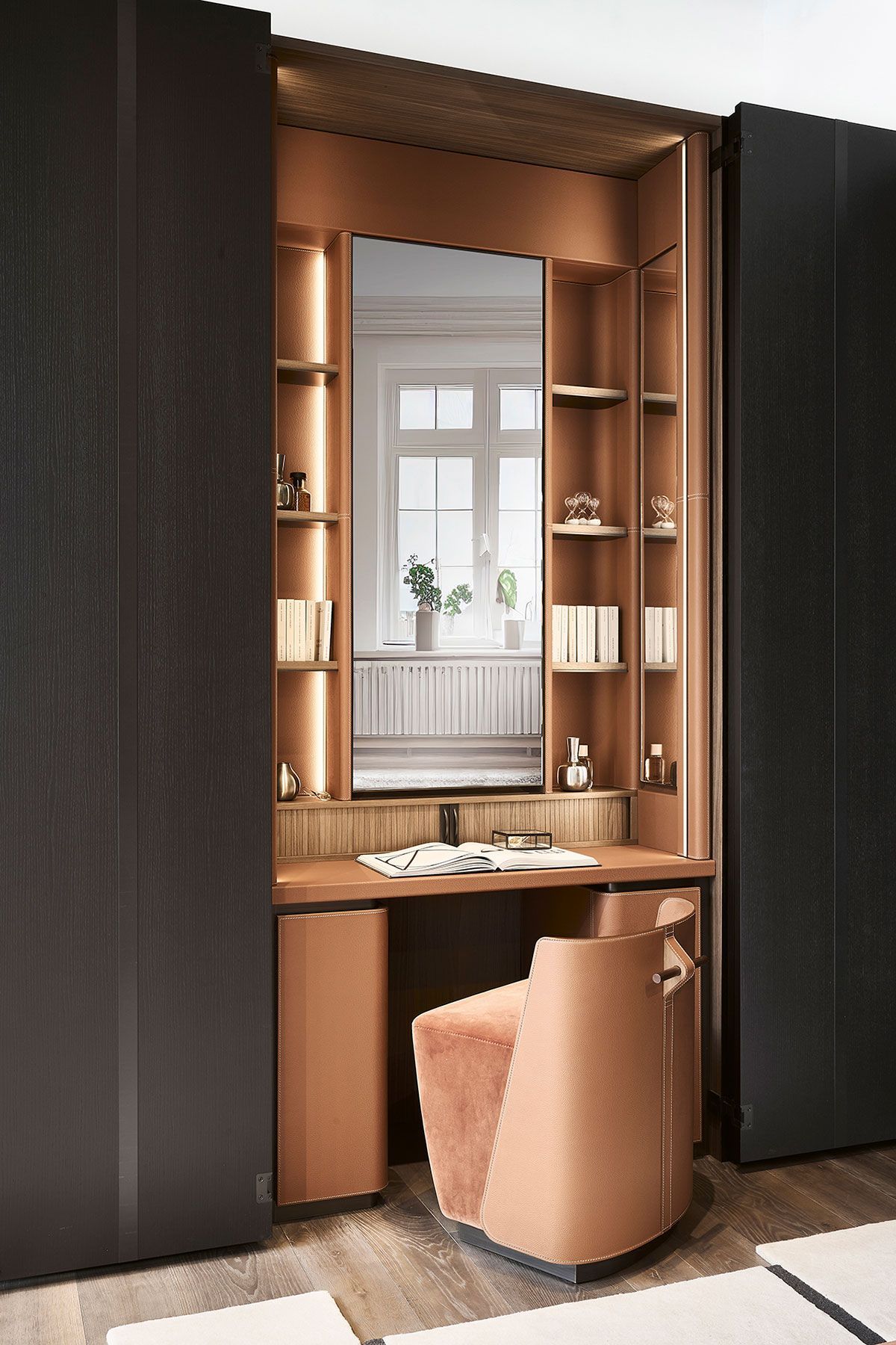 Tocador empotrado con estantes de madera, espejo y silla de color beige entre paneles de armario oscuros.