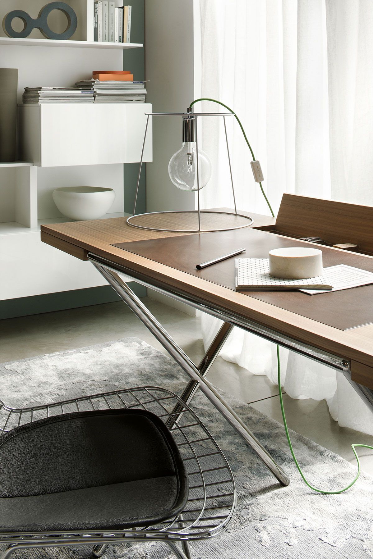 Sala de estar moderna con una mesa de centro de madera, una silla de alambre, estanterías blancas y una lámpara colgante