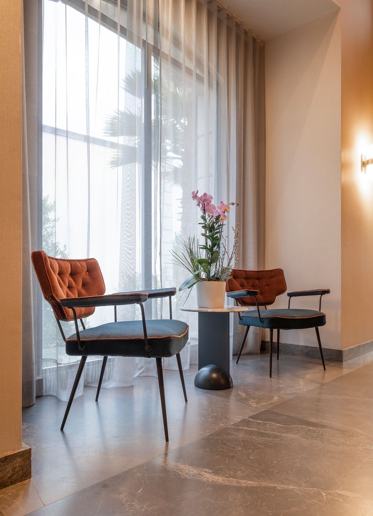Salón moderno con dos sillas negras, cojines naranjas, una pequeña mesa redonda