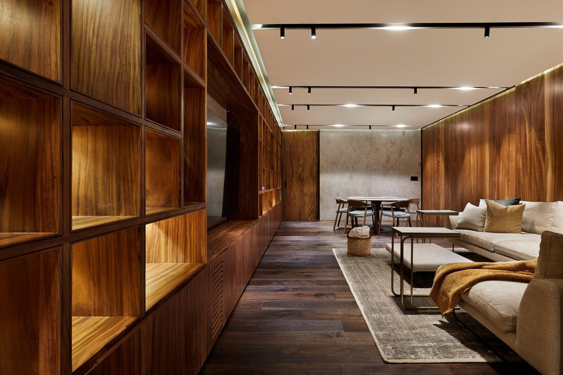 Salón de hotel moderno con paredes revestidas de madera, estanterías empotradas y asientos de color beige