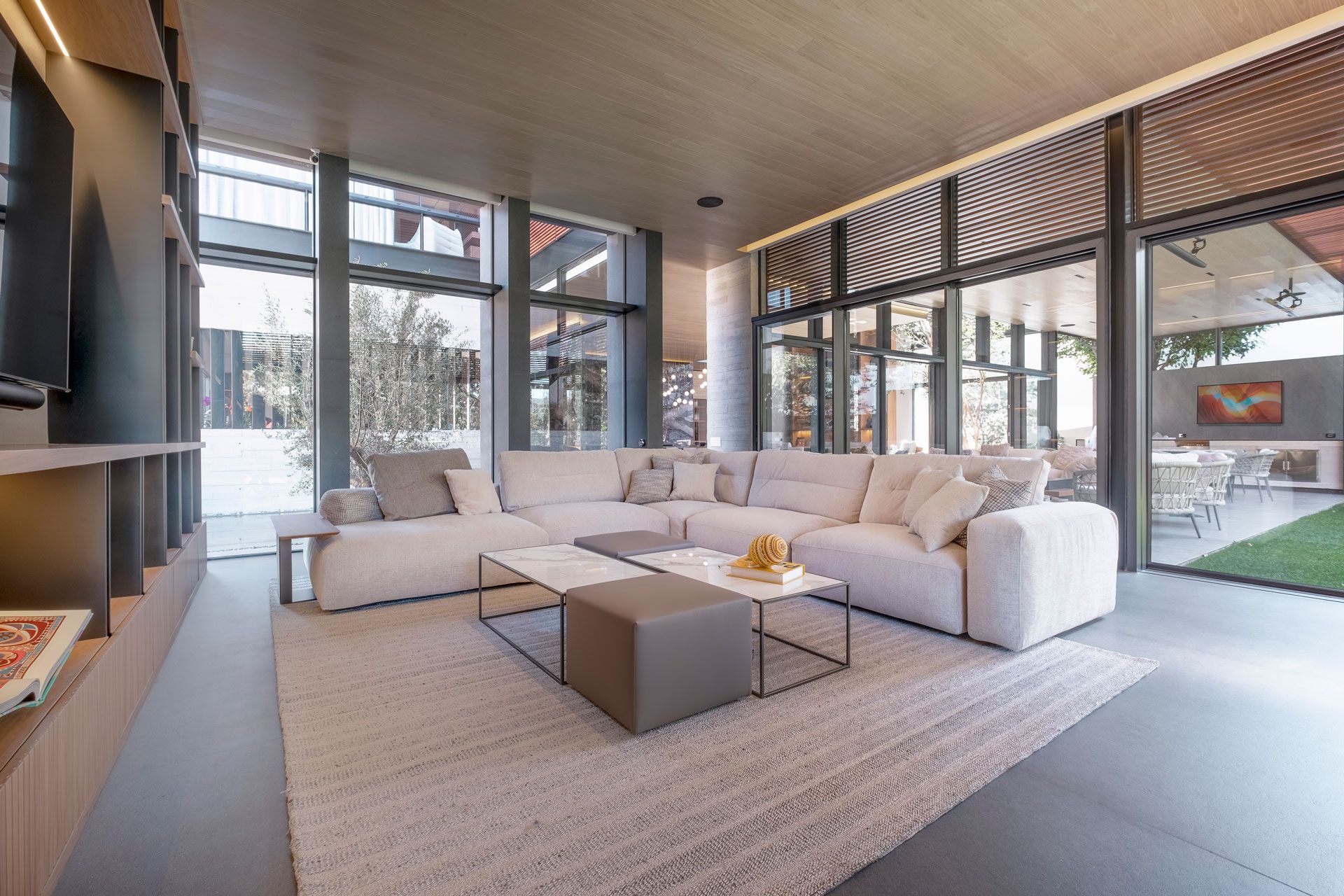 Sala de estar moderna con sofá modular blanco, grandes ventanales y chimenea.