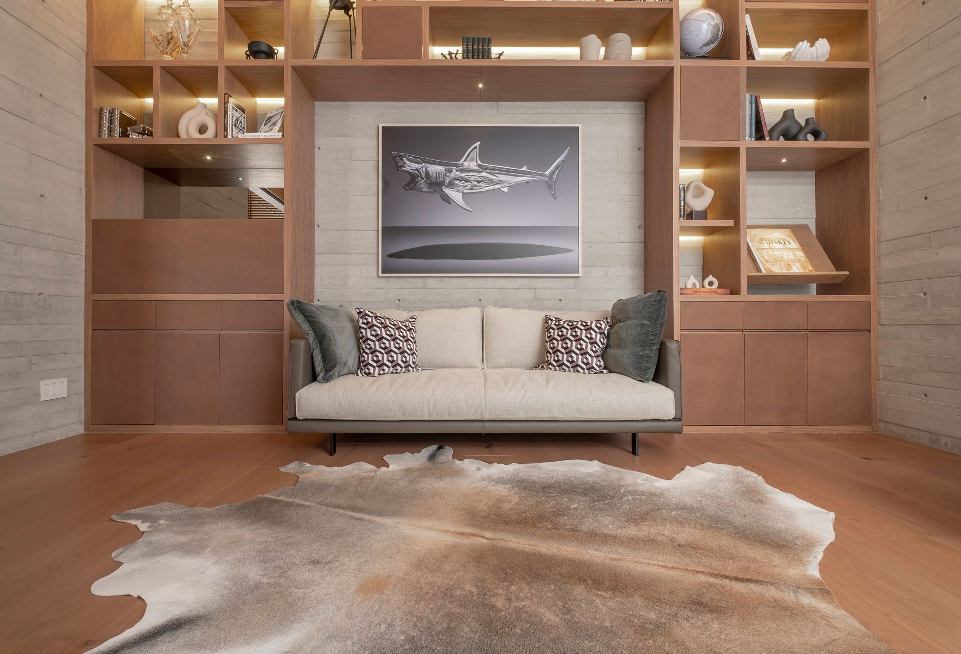 Sala de estar moderna con estanterías empotradas, sofá beige, cuadros enmarcados y una alfombra de piel