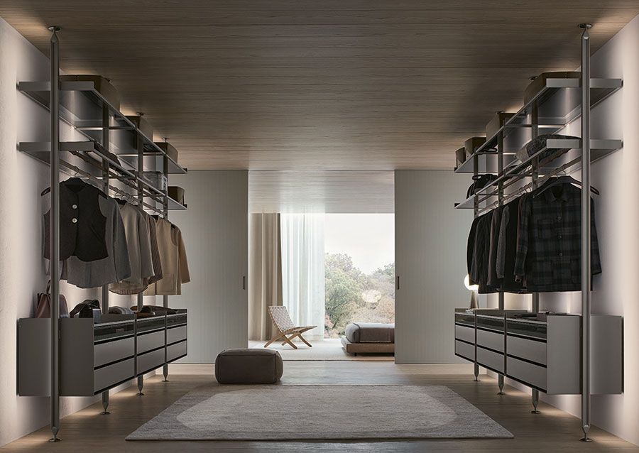 Vestidor moderno con espacio para ropa a ambos lados y vista a una luminosa zona de dormitorio.