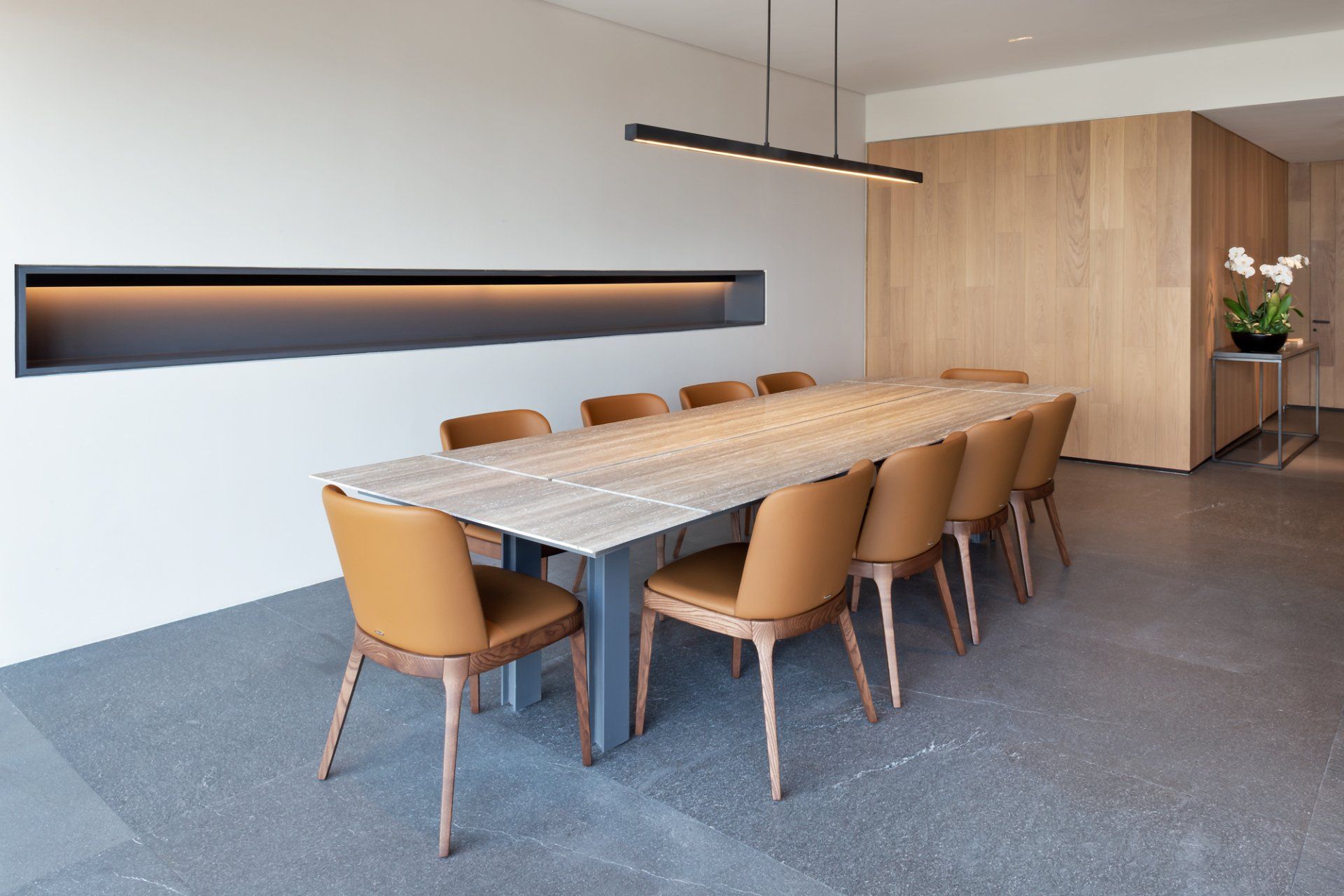 Sala de conferencias moderna con una mesa larga de madera, sillas color canela, aplique de pared y pared decorativa
