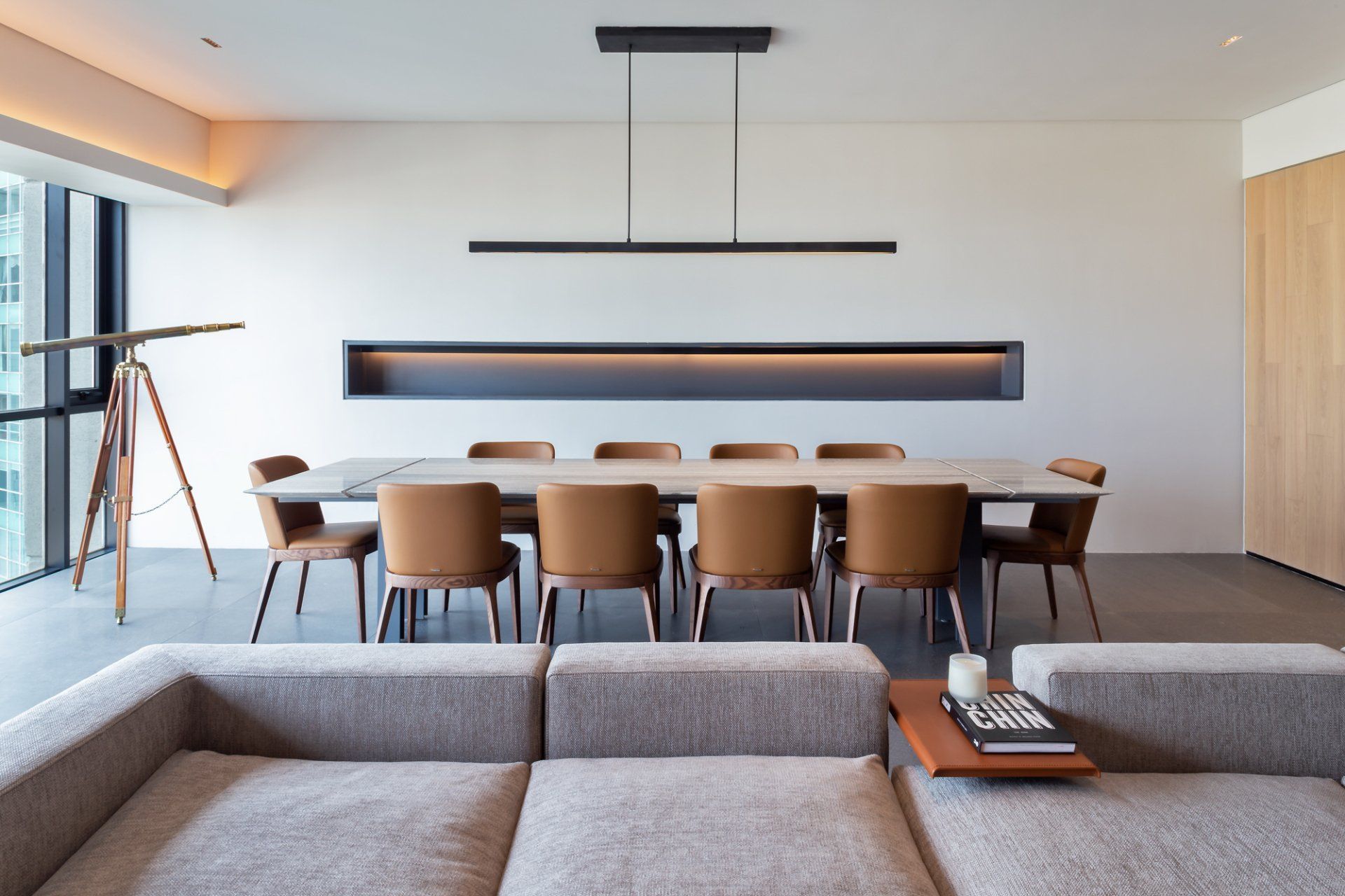 Comedor moderno con una mesa larga de madera, sillas de color tostado y lámparas colgantes negras minimalistas