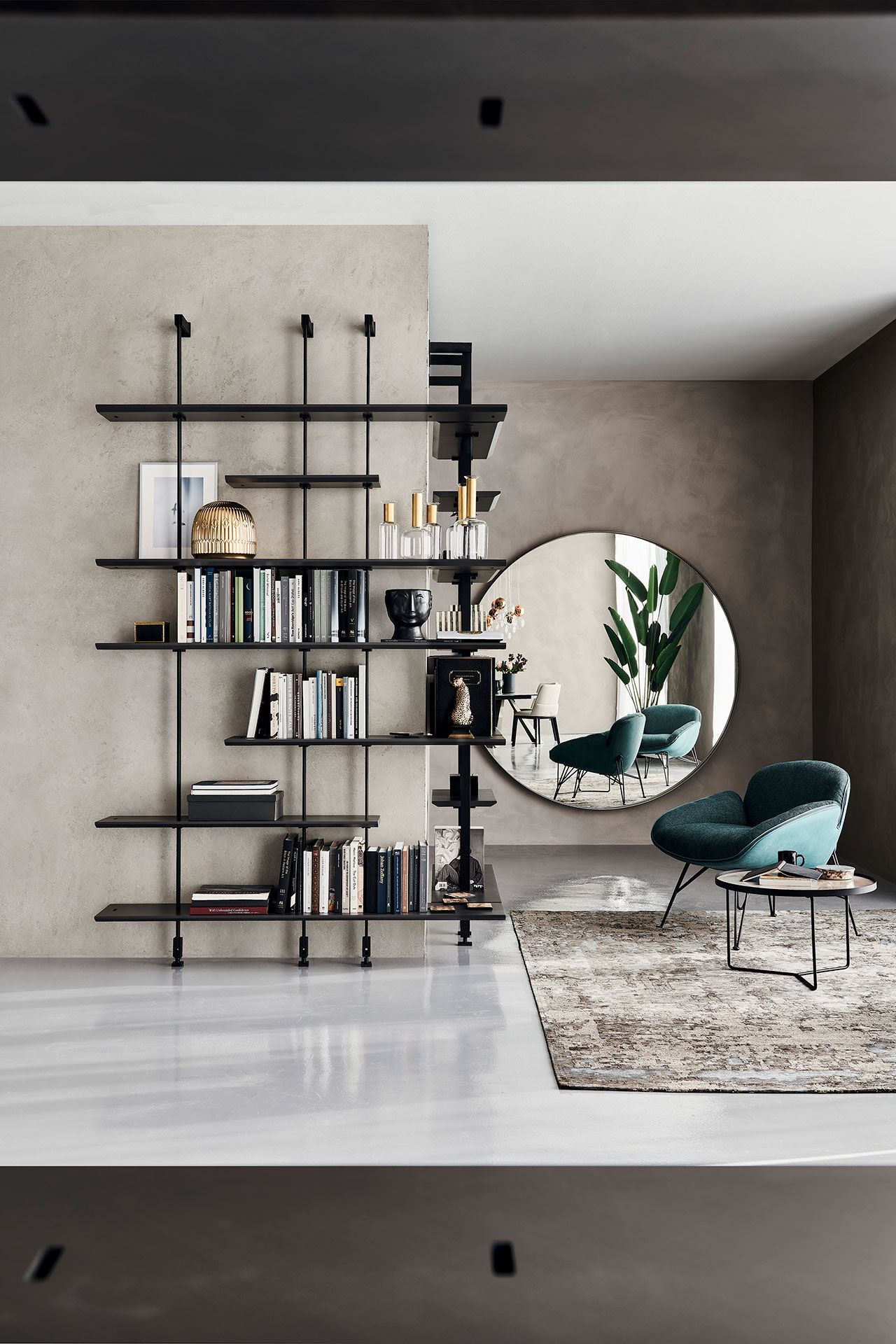 Sala de estar moderna con estantería negra, espejo redondo, silla color turquesa y paredes texturizadas grises.