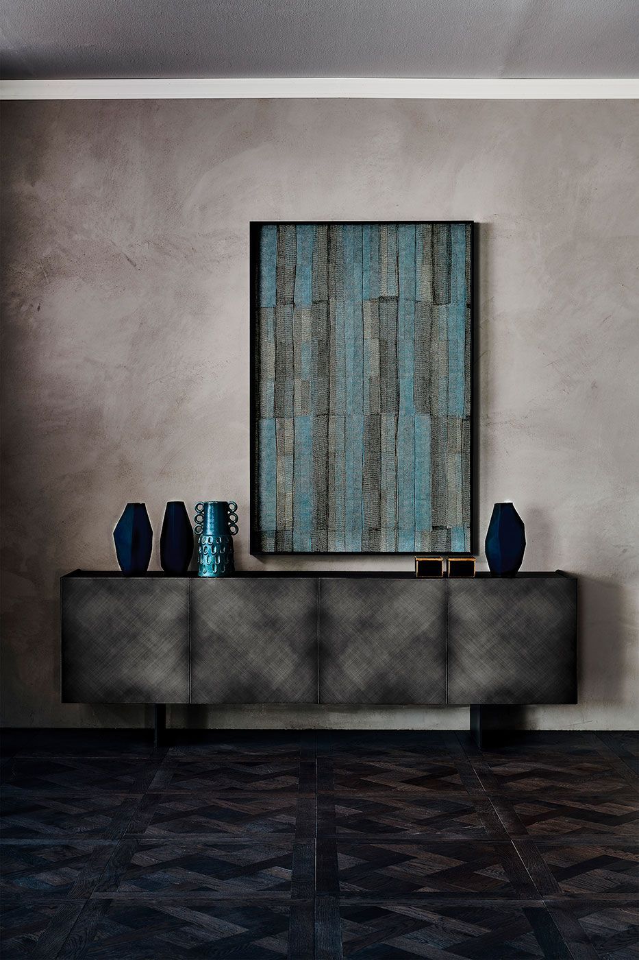 Mesa consola moderna con decoración azul y arte abstracto en la pared en una habitación gris.