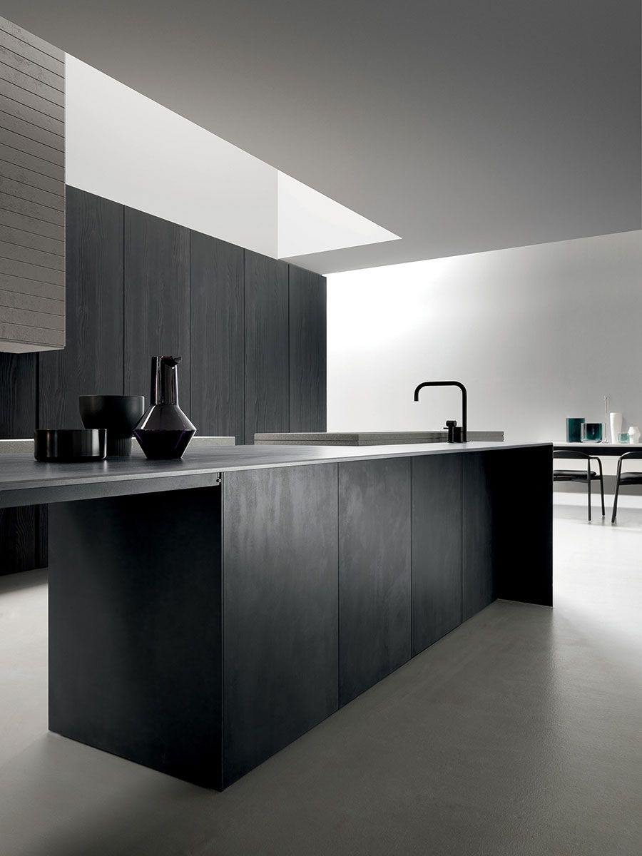 Cocina moderna minimalista en blanco y negro con isla, armarios oscuros y un grifo elegante.