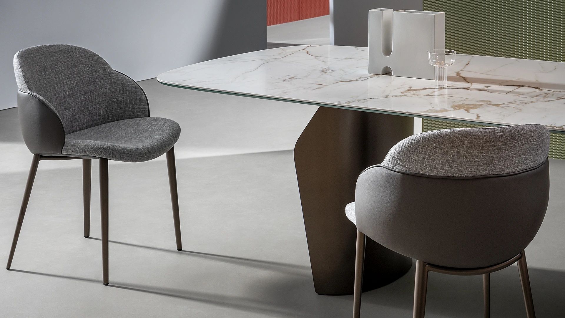 Mesa de comedor moderna con dos sillas tapizadas en gris en una habitación minimalista.
