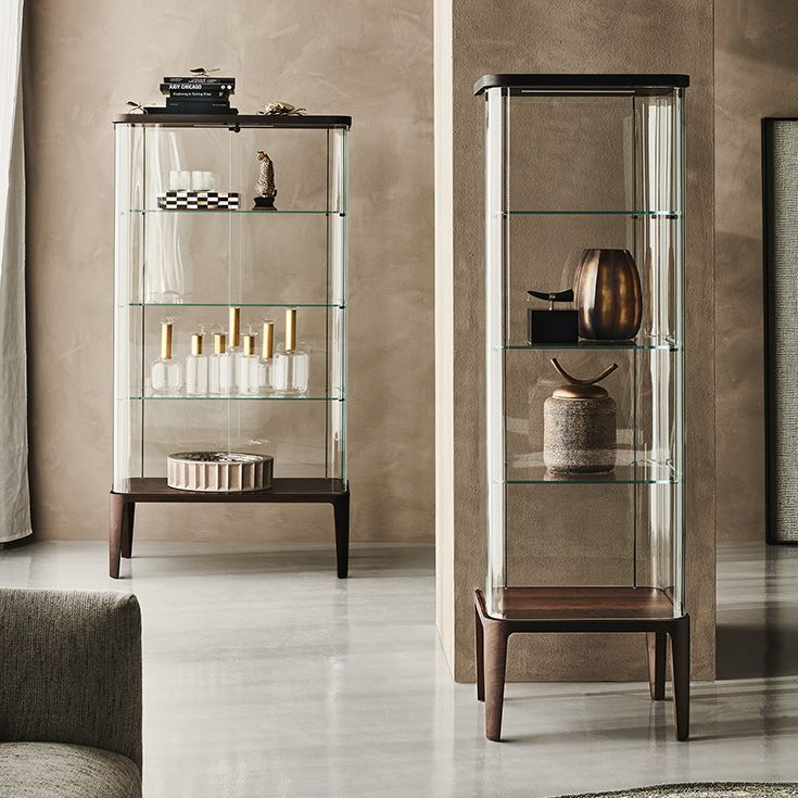 Dos estrechas vitrinas de cristal con marcos de madera oscura que contienen velas y elementos decorativos