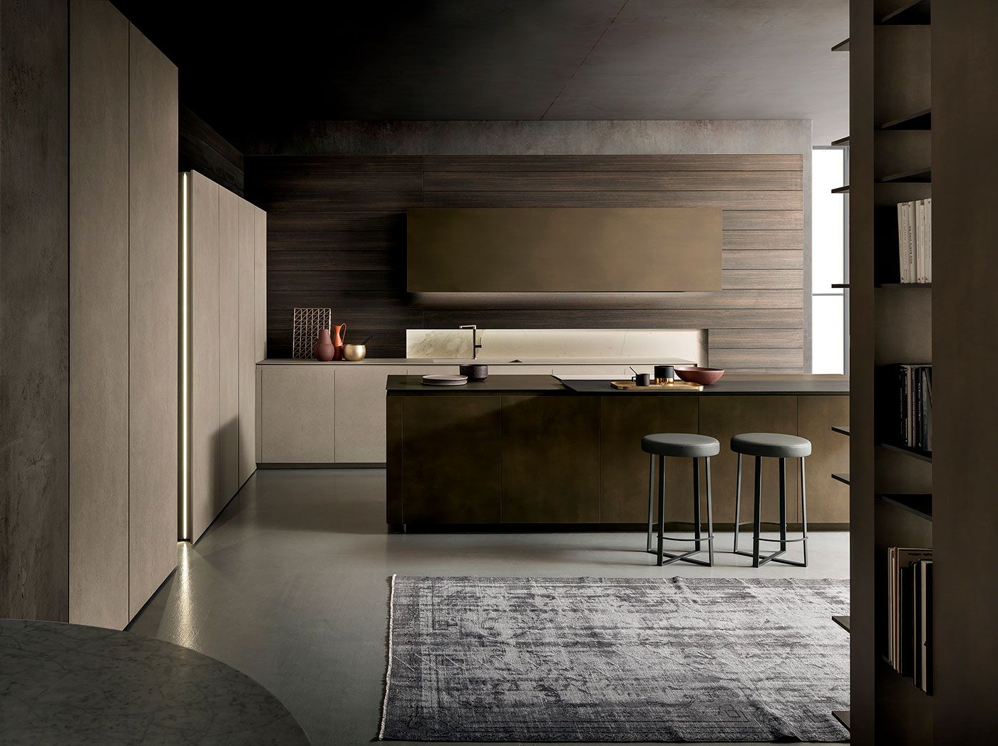 Interior de cocina moderno con gabinetes de madera oscura, taburetes en la isla y una alfombra grande bajo iluminación tenue.