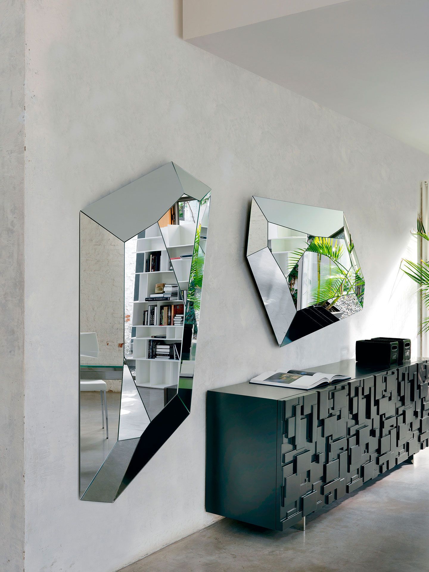 Pasillo moderno con espejos geométricos en la pared y una consola oscura texturizada con elementos decorativos.