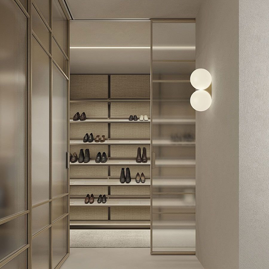 Vestidor moderno con estantes para zapatos, puertas corredizas de vidrio y apliques de pared.