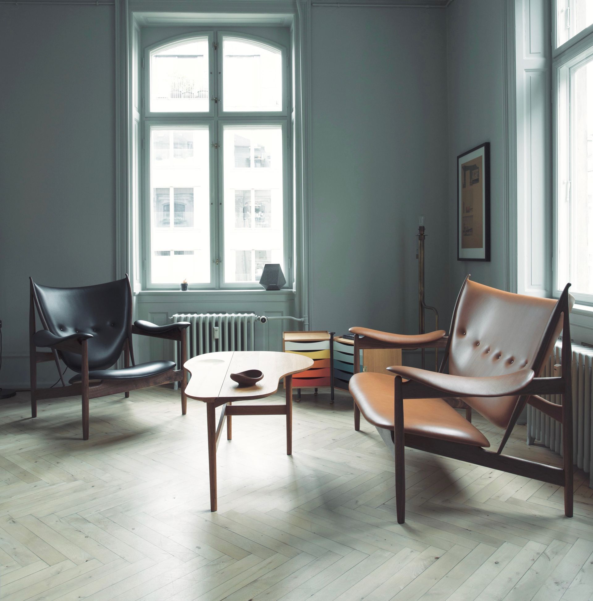 Sala de estar minimalista con dos sillones, una mesa de centro y grandes ventanales que dejan pasar una luz natural suave.